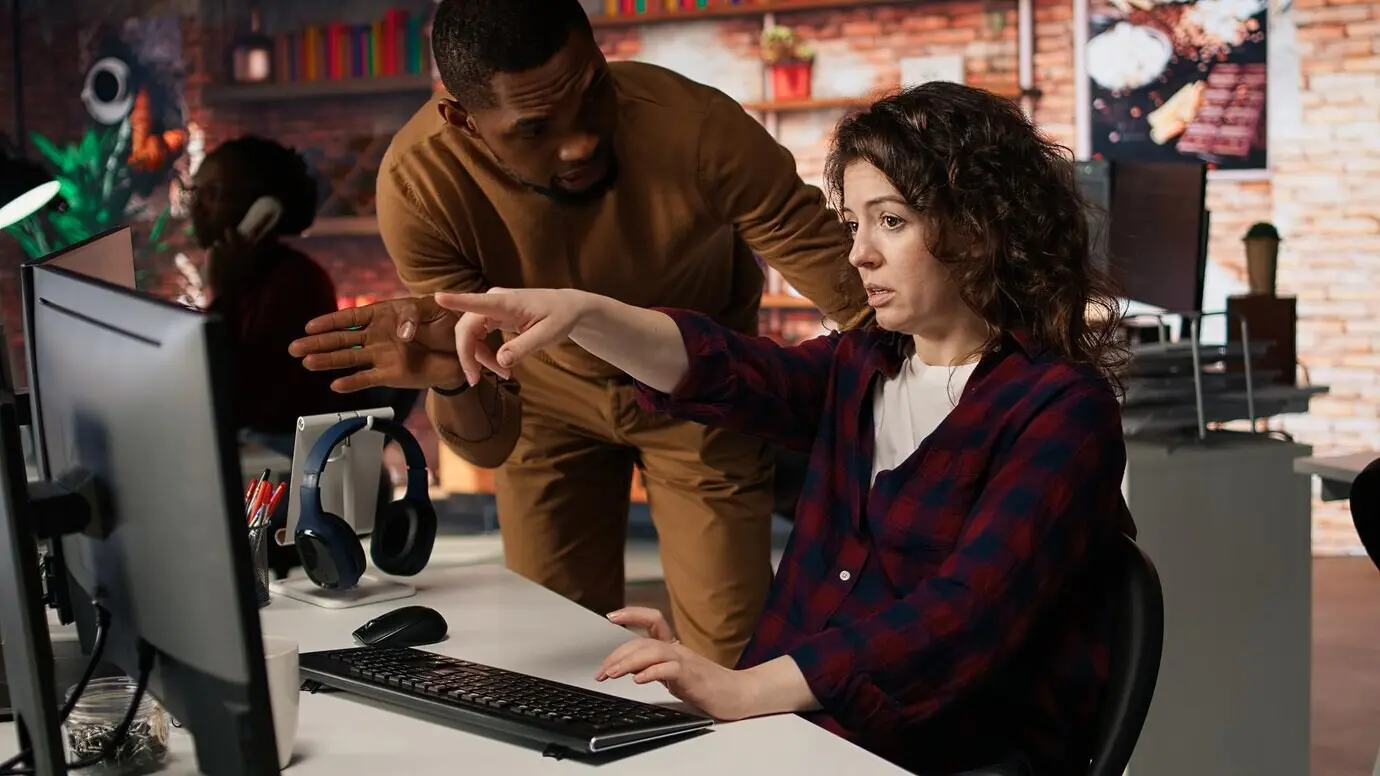 Ein Vorgesetzter in einem Start-up-Büro überprüft einen IT-Experten, der künstliche Intelligenz einsetzt.